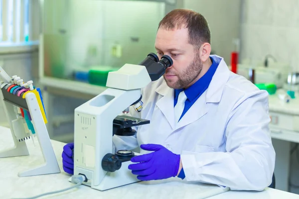 Especialista mirando a través del microscopio realizando investigación científica en un laboratorio. Prueba de orina. COVID-19. COVID Coronavirus —  Fotos de Stock