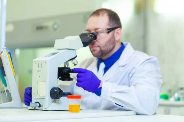 Trabajador de laboratorio que realiza análisis de orina utilizando microscopio y equipo de laboratorio en un laboratorio médico —  Fotos de Stock