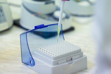 Laboratuvar çalışanı numuneleri bir tıbbi laboratuvarda bağışıklık virüsleri için analiz yapan bir tepsiye koyar. COVID-19. COVID Coronavirüs