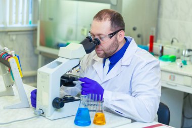 Mikroskopla inceleyen bir uzman bir laboratuarda bilimsel araştırma yapıyor. İdrar testi. COVID-19. COVID Coronavirüs