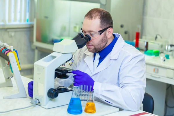 Especialista mirando a través del microscopio realizando investigación científica en un laboratorio. Prueba de orina. COVID-19. COVID Coronavirus —  Fotos de Stock