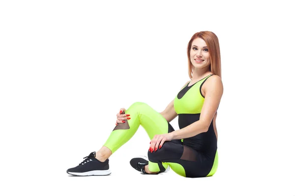 Side view portrait of beautiful fit sporty girl sitting in modern sportswear looking at camera isolated on white background — Stock Photo, Image