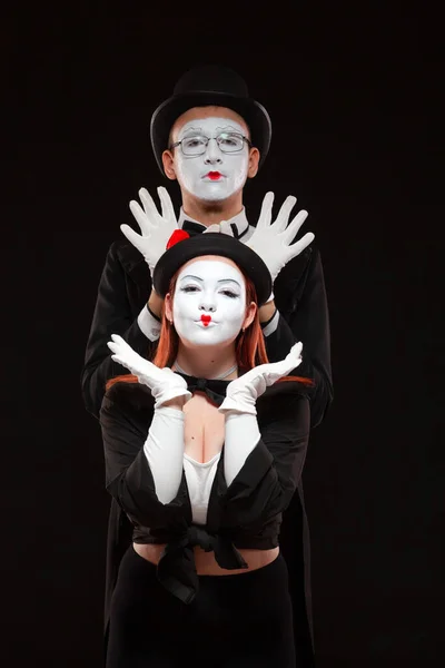Portret dwóch artystów mimów występujących na czarnym tle. Mężczyzna stoi za kobietą podnoszącą ręce nad głowę. Wygłupianie się — Zdjęcie stockowe