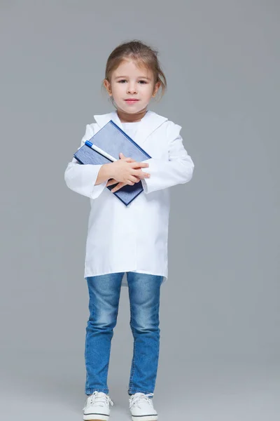 Adorable niña uniformada como médico está sosteniendo historial médico aislado sobre fondo gris —  Fotos de Stock