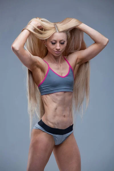 スポーツウェアの女の子は完璧なABS樹脂を示しています。フィットネス若いです女性ポルノの彼女の髪絶縁上のグレーの背景 — ストック写真