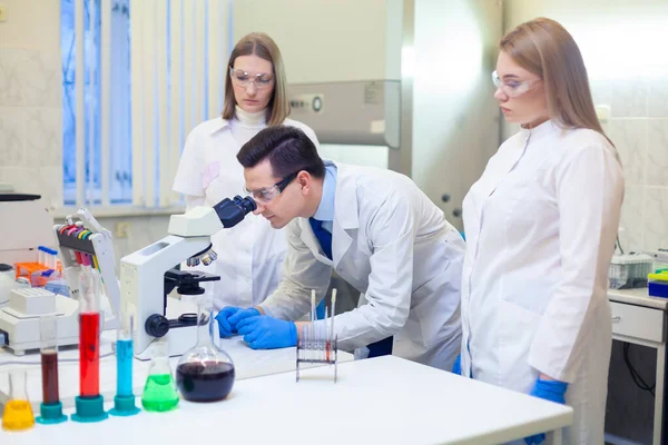 Un grupo de científicos lleva a cabo investigaciones en un laboratorio científico utilizando tecnología avanzada. COVID-19. COVID Coronavirus —  Fotos de Stock