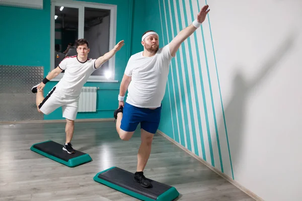 在集体健身课上，胖男人非常刻苦地在台阶上练习。体重超标 — 图库照片