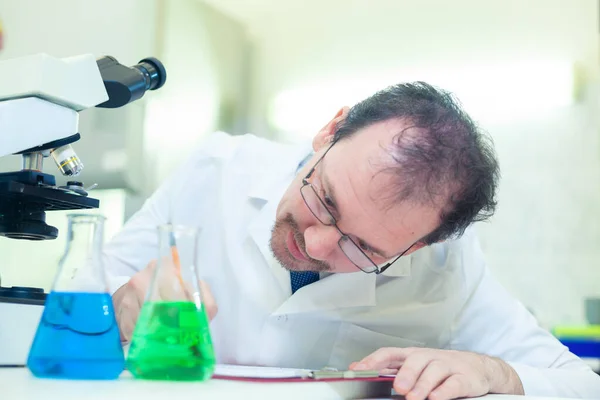 Kemist galen. En galen vetenskapsman utför experiment i ett vetenskapligt laboratorium. Avsiktligt registrera resultaten av studien. COVID-19. COVID Coronavirus — Stockfoto