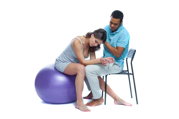 A young black man helps his white wife with birth pain with a ball. Partnered birth, partnered delivery. Isolated white background. — Stock Photo, Image