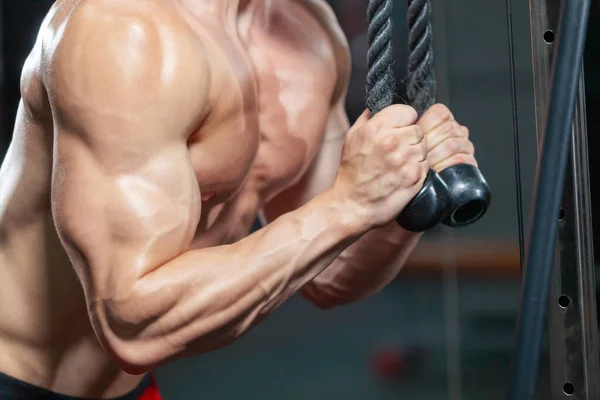 Close up de homem musculoso forte treinando seu tríceps usando equipamentos esportivos no ginásio moderno — Fotografia de Stock