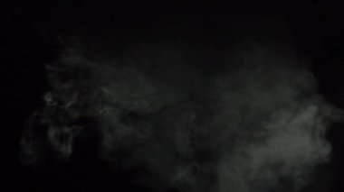 Atmosferik duman sis etkisi. Belirsiz bir geçmişi var. Soyut duman bulutu. Siyah arka planda ağır çekimde duman. Beyaz duman siyah arkaplana karşı uzayda yavaşça süzülüyor.