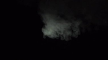 Atmosferik duman sis etkisi. Belirsiz bir geçmişi var. Soyut duman bulutu. Siyah arka planda ağır çekimde duman. Beyaz duman siyah arkaplana karşı uzayda yavaşça süzülüyor.