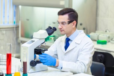 Bilimadamı bir tıp laboratuarında mikroskop altında bilimsel araştırmalar yapıyor. COVID-19. COVID Coronavirüs