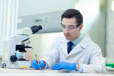 Bilim adamı, bir tıp laboratuarında mikroskop ve laboratuvar ekipmanları kullanarak Omega 3 yağ asitlerinin özelliklerini ve faydalarını araştırıyor. COVID-19. COVID Coronavirüs