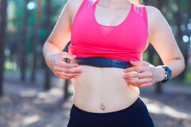 Ormanda egzersiz yapmak için kalp atış hızı monitörünü kullanan ya da kilo verişini takip eden bir kıza yakın durun.