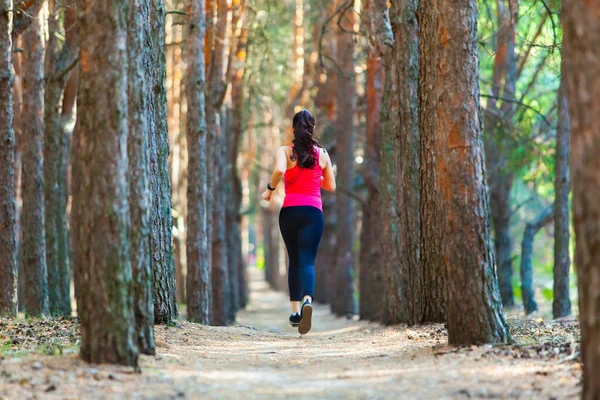 Back view of young woman runner training alone outdoors in the summer forest — Stock Photo, Image