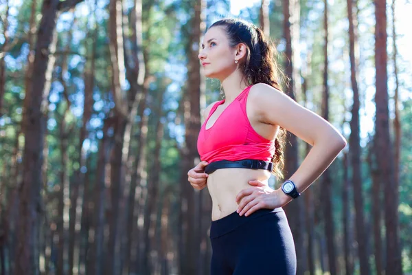Fitness girl using heart rate monitor for workout in the forest or tracking her weight loss improvement — Stock Photo, Image