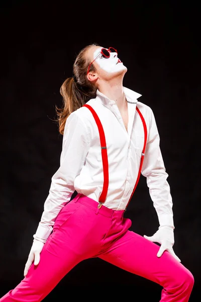 Portrait of male mime artist, isolated on black background. Man in suspenders and pink trousers is posing touching his stomach. Symbol of popular, dance, 90s — Stock Photo, Image