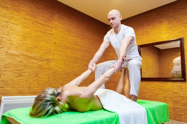 Angle view lövés masszőr húzza női karok csinál hagyományos thai masszázs női test a spa szalonban. Szépségkezelési koncepció — Stock Fotó