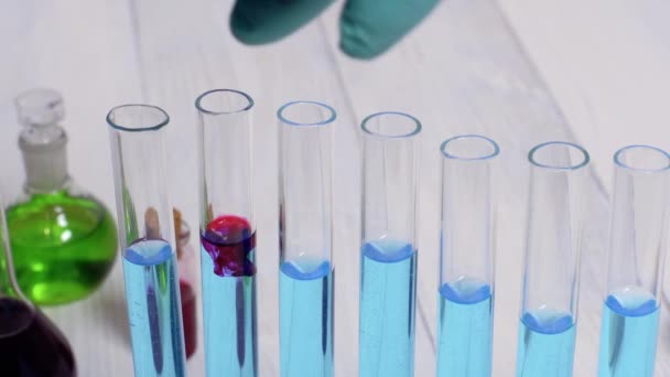 Ilmuwan menuangkan pereaksi ke dalam tabung reaksi untuk pengujian di laboratorium kimia. Indah reaksi merah larut dalam biru. — Stok Video