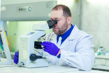 Mikroskopla inceleyen bir uzman bir laboratuarda bilimsel araştırma yapıyor..