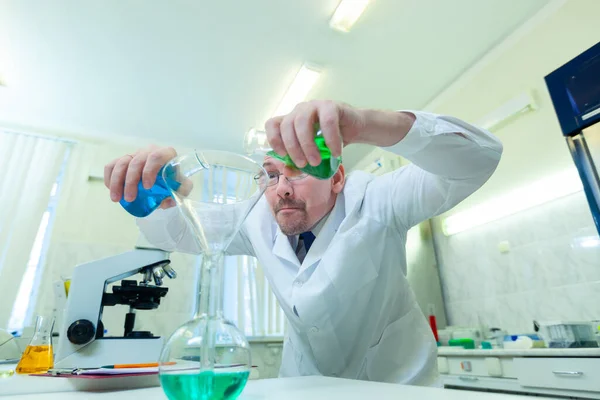 Chemist crazy. A mad scientist conducts experiments in a scientific laboratory. With a mad expression on his face, he mixes two liquids in a flask. COVID-19. COVID Coronavirus