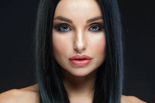 Close-up van mooie vrouw gezicht met schoonheid make-up en lange brunette haar op zoek naar camera geïsoleerd op zwarte achtergrond — Stockfoto