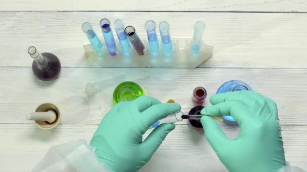 Ilmuwan menjatuhkan pereaksi ke dalam tabung reaksi untuk pengujian di laboratorium kimia. — Stok Video