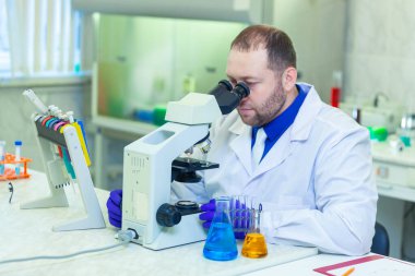Mikroskopla inceleyen bir uzman bir laboratuarda bilimsel araştırma yapıyor. İdrar testi. COVID-19. COVID Coronavirüs