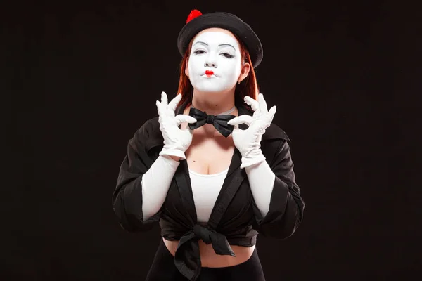 Portrait of female mime artist performing, isolated on black background. Woman is showing confidence touching her bow tie — Stock Photo, Image