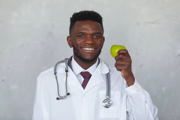 Black man doctor with green apple in the hand is ready to fight against the COVID, COVID-19, coronavirus, pandemic, epidemic, virus. Concept of humanitarian assistance to African countries
