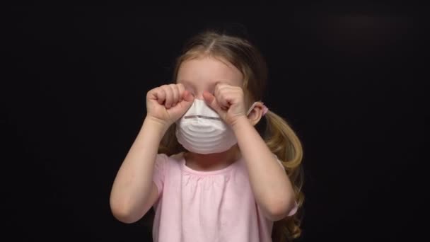 Концепция коронавируса и загрязнения воздуха. Маленькая девочка в маске для защиты. Коронавирус Ухана и симптомы эпидемии вируса. Плачет и боится COVID-19. Изолированный на черном фоне . — стоковое видео
