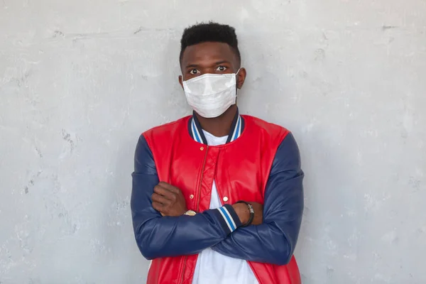Tıbbi maske takan yakışıklı Afrikalı bir adamın portresi gri arka planda 2019 numaralı koronavirüs tehlikesiyle şok oldu. — Stok fotoğraf