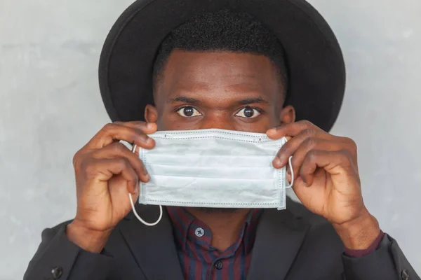 COVID, COVID-19, koronavirüs, salgın. Genç Afrikalı adam koronavirüs enfeksiyonu ve salgını önlemek için koruyucu bir maske takacak. — Stok fotoğraf