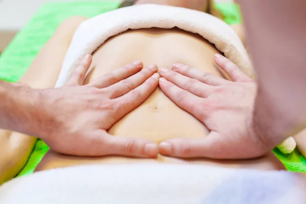 Visão superior das mãos massageando abdômen feminino. Terapeuta a pressionar a barriga. Mulher recebendo massagem no salão de spa — Fotografia de Stock