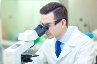 Bilimadamı bir tıp laboratuarında mikroskop altında bilimsel araştırmalar yapıyor. COVID-19. COVID Coronavirüs