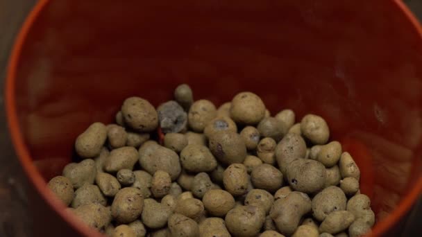 Close-up van bruine pot met afvoer. Persoon voegt drainage met zijn hand, dan zet grond in de pot met troffel — Stockvideo