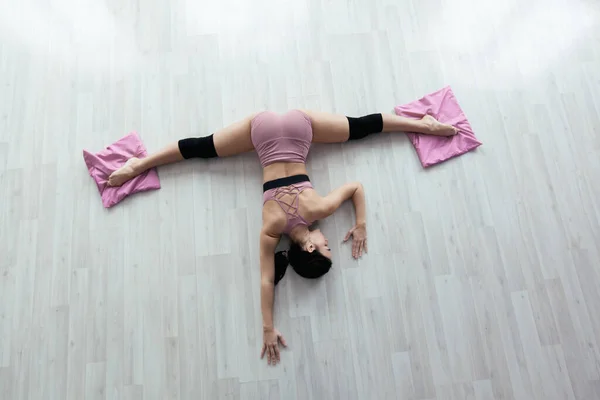 Mladá fitness žena dělá protahování cvičení ležící na podlaze s nohama na rohožích — Stock fotografie