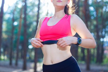 Ormanda egzersiz yapmak için kalp atış hızı monitörünü kullanan ya da kilo verişini takip eden bir kıza yakın durun.