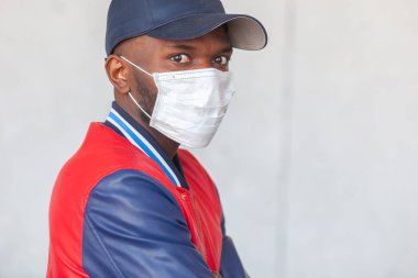 Yakından çekilen fotoğrafta şapkalı ve günlük kıyafetler giyen yakışıklı Afrikalı adam Coronavirus 2019 tehlikesiyle şok olmuş.