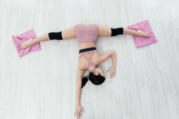 Молода фітнес-леді розтягує вправи лежачи на підлозі з ногами на килимках — стокове фото