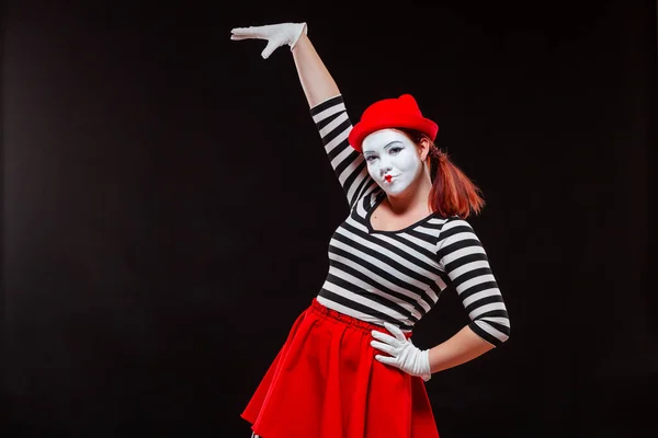 Portrait of female mime artist performing, isolated on black background. Woman raised her hand up. A symbol of growth, high interest rates, high income, large size