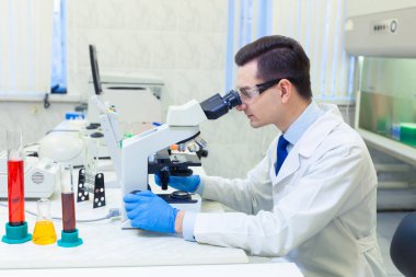 Bilimadamı bir tıp laboratuarında mikroskop altında bilimsel araştırmalar yapıyor. COVID-19. COVID Coronavirüs