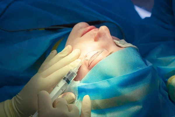Χειρουργός εισάγει μια ένεση στο κάτω βλέφαρο του ασθενούς πριν από την εκτέλεση της λειτουργίας ανύψωσης των βλεφάρων. Βλεφαροπλαστική — Φωτογραφία Αρχείου