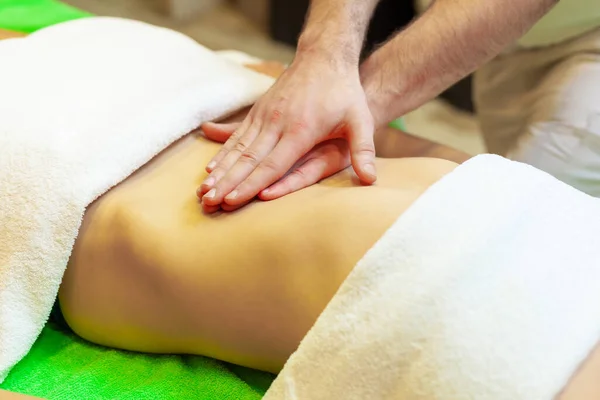 Vista lateral das mãos massagear o abdômen feminino. Terapeuta a pressionar a barriga. Mulher recebendo massagem no salão de spa — Fotografia de Stock