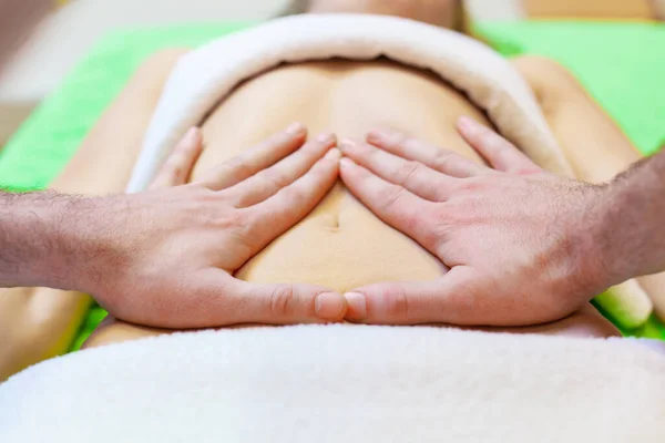 Bovenaanzicht van handen masseren vrouwelijke buik. Therapeut oefent druk uit op de buik. Vrouw krijgt massage in spa salon — Stockfoto