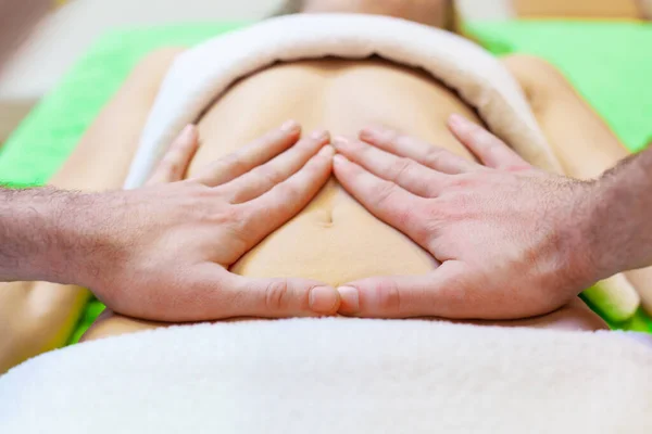 Visão superior das mãos massageando abdômen feminino. Terapeuta a pressionar a barriga. Mulher recebendo massagem no salão de spa — Fotografia de Stock