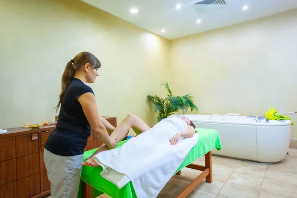 Professionell terapeut ger avslappnande zonterapi Thailändsk olja ben massage behandling till en kvinna i spa — Stockfoto