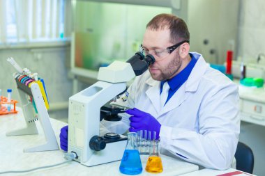 Mikroskopla inceleyen bir uzman bir laboratuarda bilimsel araştırma yapıyor. İdrar testi. COVID-19. COVID Coronavirüs