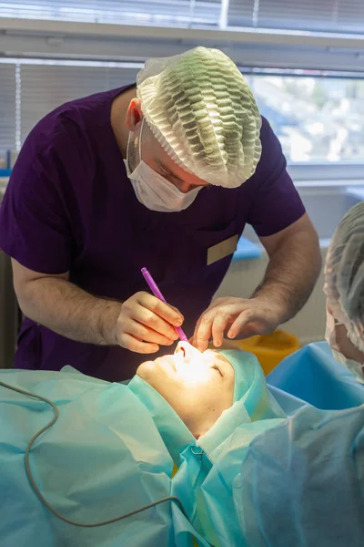 Cirujano masculino hace marcas quirúrgicas en la cara del paciente antes de la cirugía de blefaroplastia —  Fotos de Stock